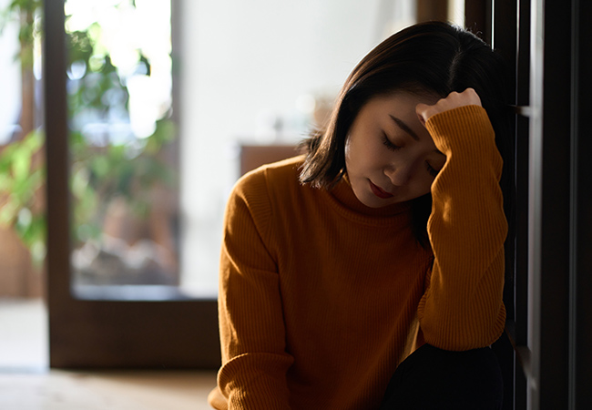 手を額に当てうつむく女性